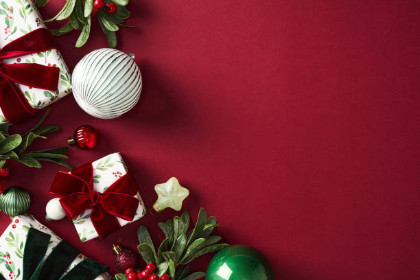 istock Christmas flat lay composition with festive decorations on a red backdrop featuring gift boxes, ornaments, and holly. Perfect for holiday marketing, greeting cards, and seasonal promotions 2181489418