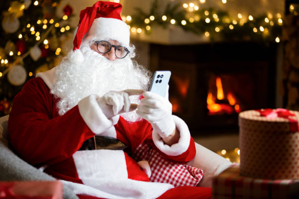 Jolly Santa Claus with eyeglasses scrolls his smartphone, reads heartfelt letters by a cozy fireplace in a cozy festive room with Christmas tree, decorated by twinkling lights. Coming holiday vibes el alegre papá noel con anteojos desplaza su teléfono inteligente, lee cartas sinceras junto a una acogedora chimenea en una acogedora habitación festiva con árbol de navidad, decorada con luces parpadeantes. vibraciones navideñas que se avecinan