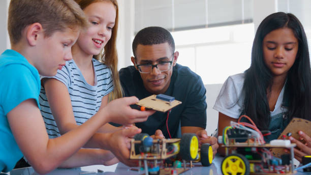 istock Students With Male Teacher In School Computer Class Building And Programming Robot Vehicle 2181490235