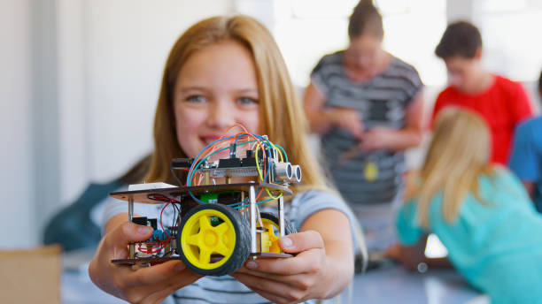istock Portrait Of Smiling Female Student Holding Robot Vehicle In School Computer Coding Class 2181490430