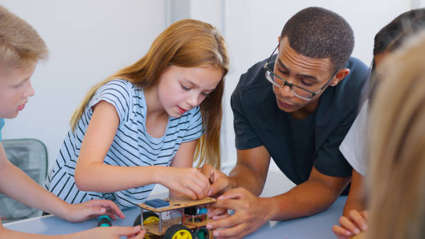 istock Students With Male Teacher In School Computer Class Building And Programming Robot Vehicle 2181490454