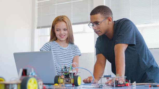 istock Female Student With Teacher With Laptop Building Robot Vehicle In School Computer Coding Class 2181490456