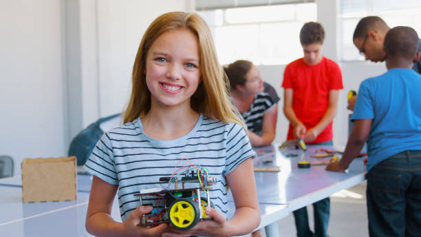 istock Portrait Of Smiling Female Student Holding Robot Vehicle In School Computer Coding Class 2181490458