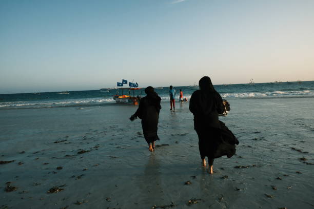 Two Somali girls walk toward the beach barefoot, holding their shoes in their hands, eager to enjoy a boat ride at Liido Beach in Mogadishu, Somalia.