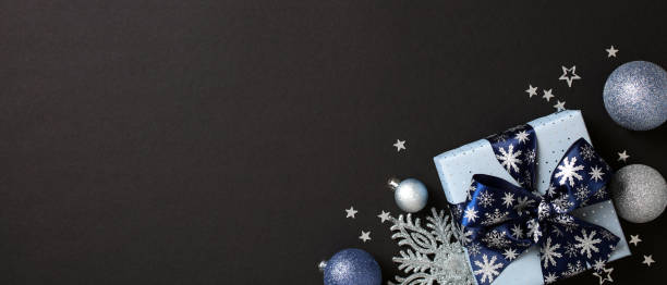 istock Christmas banner design with blue gift box and sparkling silver decorations on dark background. Flat lay, top view, copy space. 2181495436