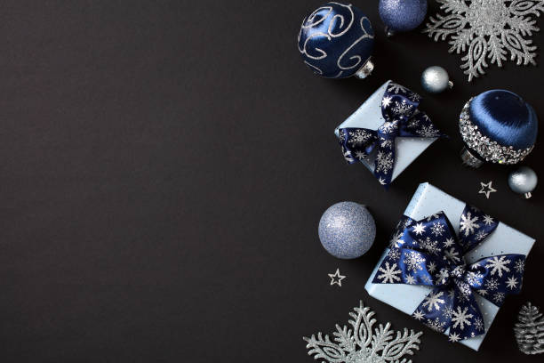 istock Elegant Christmas holiday decor with blue and silver ornaments, patterned gift boxes, and snowflakes on a dark background. Flat lay, top view, copy space. 2181495567