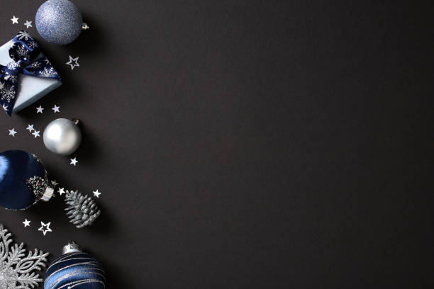 istock Luxury Christmas decor in blue and silver on black table. Includes baubles, gift boxes, pine cones, and snowflakes. Flat lay, top view, copy space. 2181495889