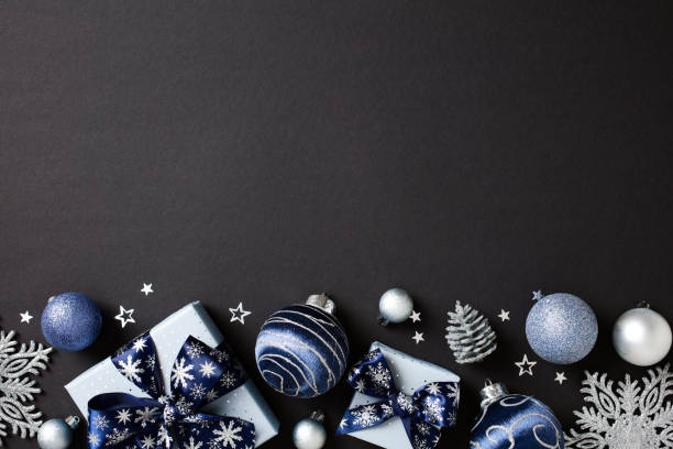 istock Christmas decorations in blue and silver, featuring baubles, gift boxes, snowflakes, and pine cones on dark table. Flat lay, top view, copy space 2181496101