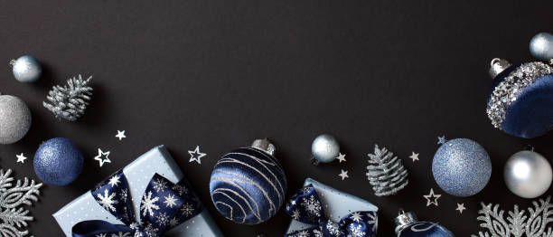 istock Blue and silver Christmas decorations with baubles, gift boxes, snowflakes, and pine cones on a dark background 2181496119