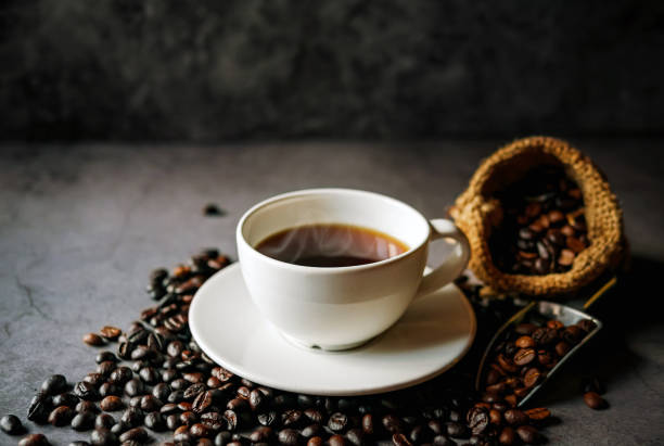 istock Americano coffee cup and roasted coffee beans falling in a burlap sackon gray background, Black coffee cup aromatic 2181496354