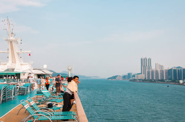 Hong Kong, China - April 27, 2009: Passengers enjoy the view from a cruise ship deck overlooking the city's skyline and waterfront.