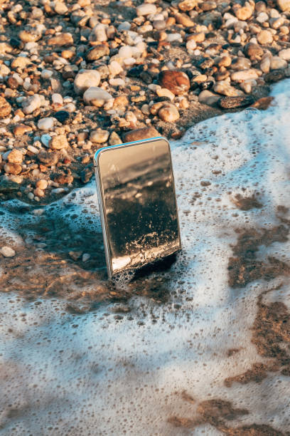 istock Lost abandoned mobile phone splashed by sea wave in summer morning 2181497035