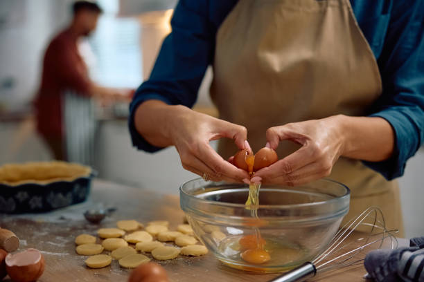 istock Close up of woman cracking an egg while baking at home. 2181502456