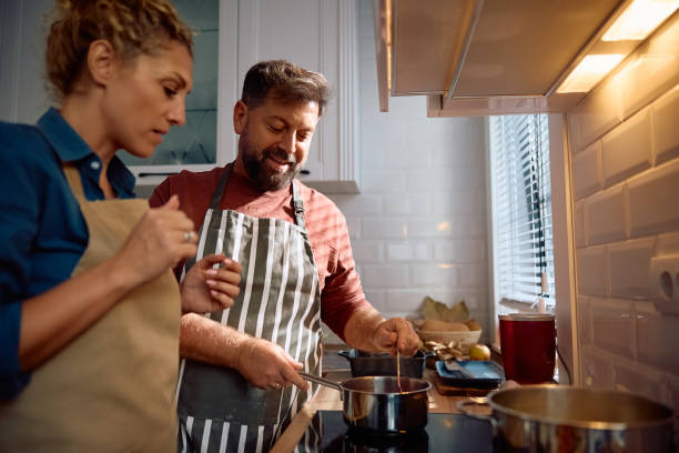 istock Smiling man making lunch with his wife in the kitchen. 2181502459
