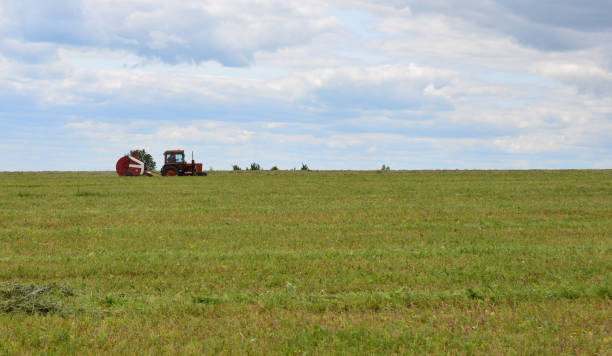 istock a tractor is in a green field is making hay bales 2181505867