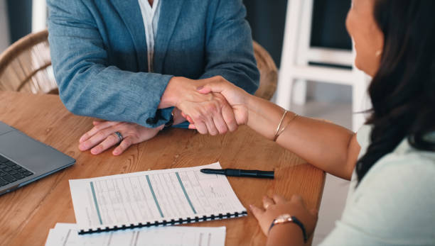 istock Real estate agent, customer and handshake with contract for lease agreement and title deed. People, male employee and female client on shaking hands with paperwork for application, form and legal 2181507316