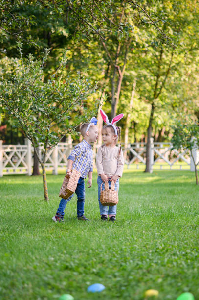 istock Children Collecting Easter Eggs Outdoors in Bunny Ears 2181510467