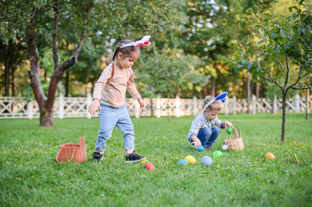 istock Children Collecting Easter Eggs Outdoors in Bunny Ears 2181510475