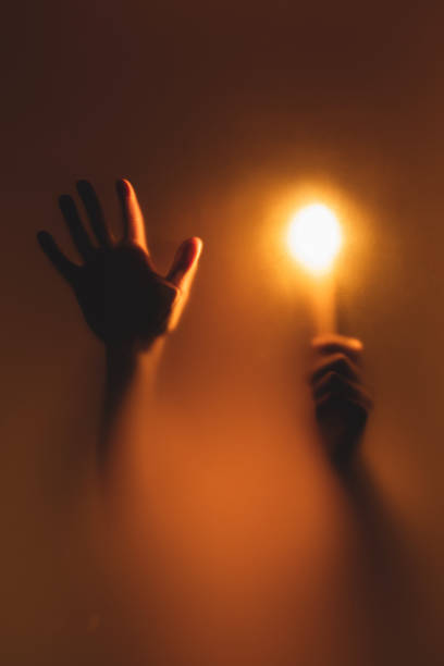 Burning candle in hand. Abstract silhouette