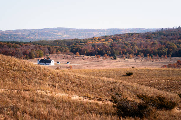 A White barn behind sand dunes in autumn