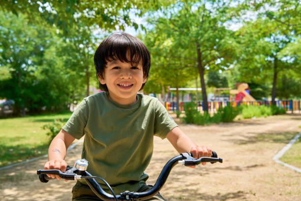 istock Smiling Latino boy riding a bicycle in a park 2181519436
