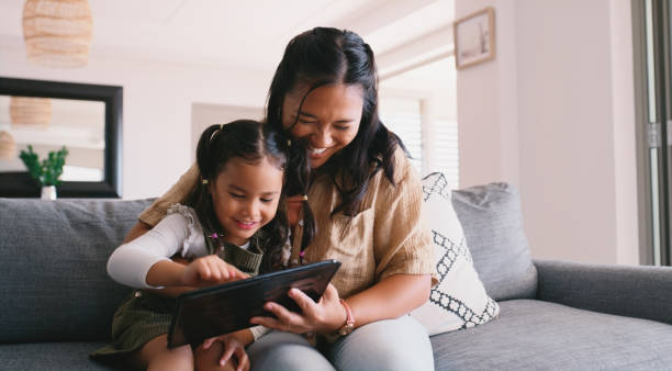 istock Woman, smile and child with tablet on sofa for development, knowledge or education game together. Living room, happy and girl with tech by mother for interactive, elearning or quiz on website at home 2181522641