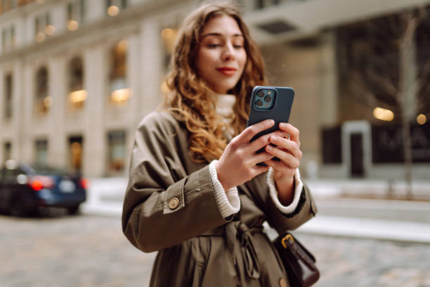 istock Stylish female browsing internet in smartphone while standing on street. 2181525049