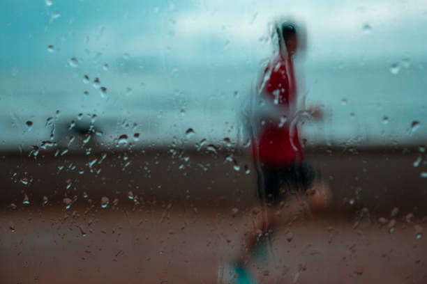 Solitary Runner Through a Rainy Windowpane on a Coastal Run