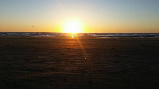 Sunset over a tranquil beach with golden hues.