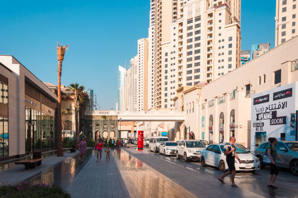 Dubai, UAE - October 17, 2016: People walking along a busy street with modern skyscrapers in the background.