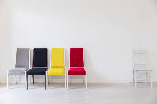 Two pink and half a green stacking chair with white seat and perforated pattern in the backrest in front of a brown house wall. Garden chairs
