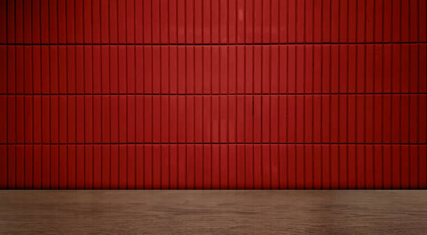 walnut wooden table at foreground with red ceramic clay wall tiles in vertical pattern at background use as product displayed backdrop. minimal modern counter mockup for product presentation.