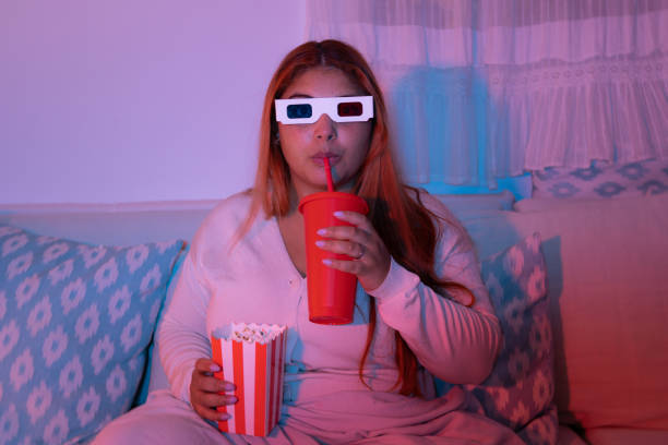istock Young woman drinking soda while watching a movie 2181537481