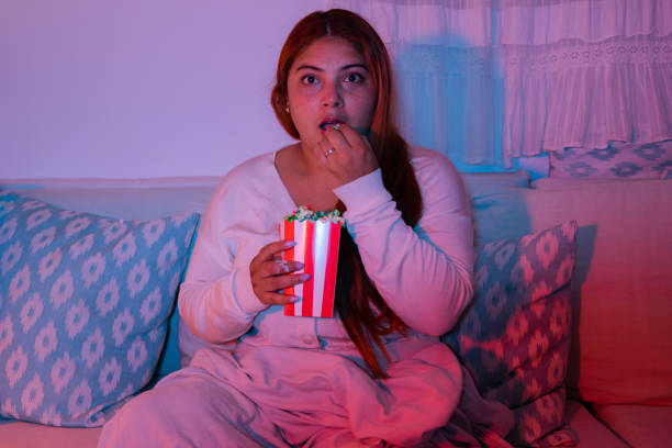 istock Young woman watching her favorite show with popcorn 2181537482