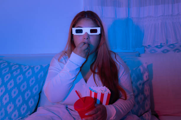 istock Young woman eating popcorn while watching a movie 2181537498