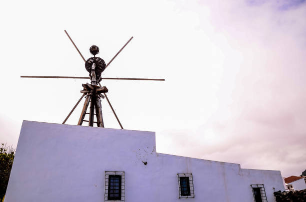 A tall windmill with a person on top of it. The windmill is surrounded by a white building