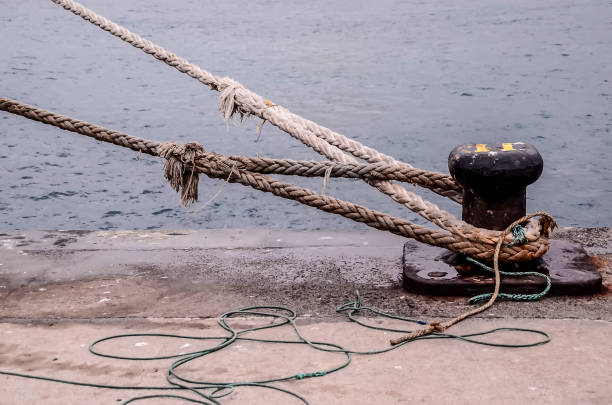 Rope anchored the boat into the harbor.Mooring rope and bollard