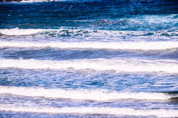 A beautiful blue ocean with white waves. The water is calm and peaceful, creating a serene atmosphere. The waves are gently rolling in, creating a sense of tranquility and relaxation
