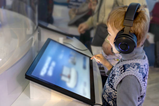 Boy wearing headphones interacts with interactive screen at an exhibit