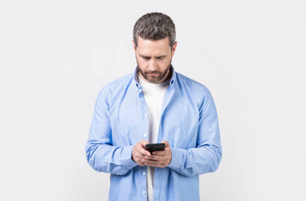 istock mature man write message on phone isolated on studio background. man with phone message 2181557151