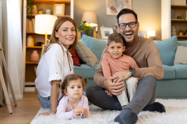 istock Happy parents with kids posing joyfully on comfortable rug 2181561534