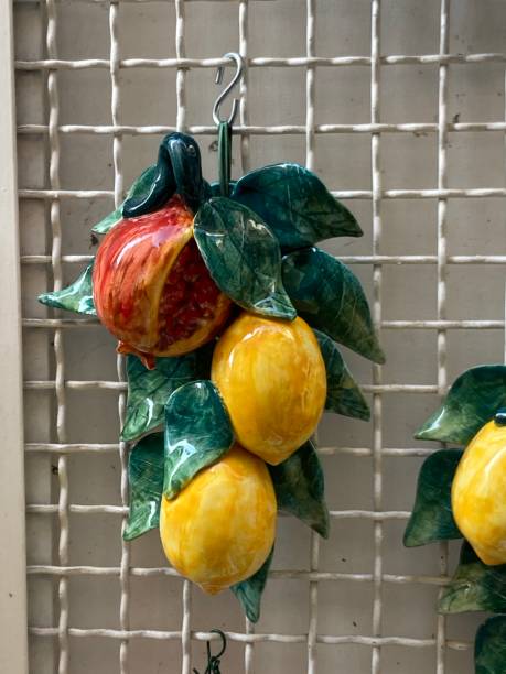 istock Close up of ceramic  lemons  and pomegranate hanging on wire mesh background. 2181562628