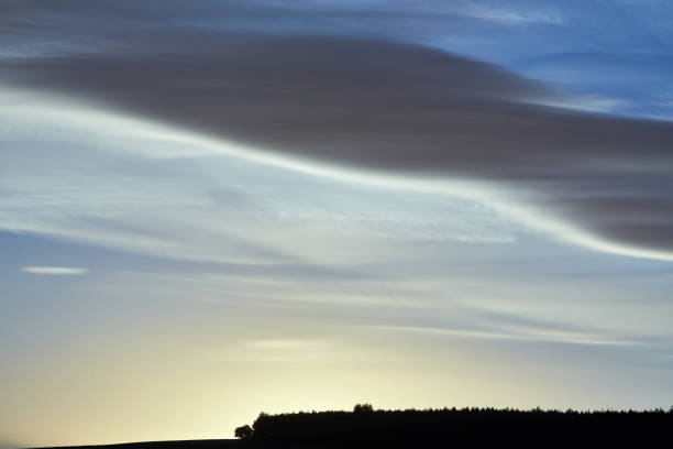 Beautiful sunrise behind a hill with atmospheric clouds in the morning sky.
