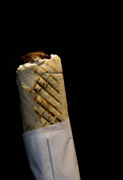istock Crispy golden kebab wrapped in paper on a black background 2181562788