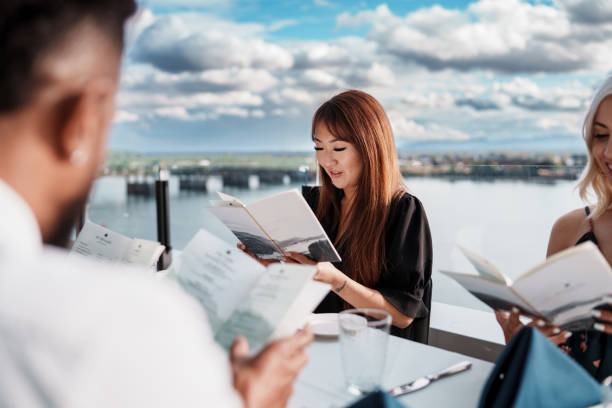 istock Beautiful woman looking at restaurant menu while dining out with friends 2181566898