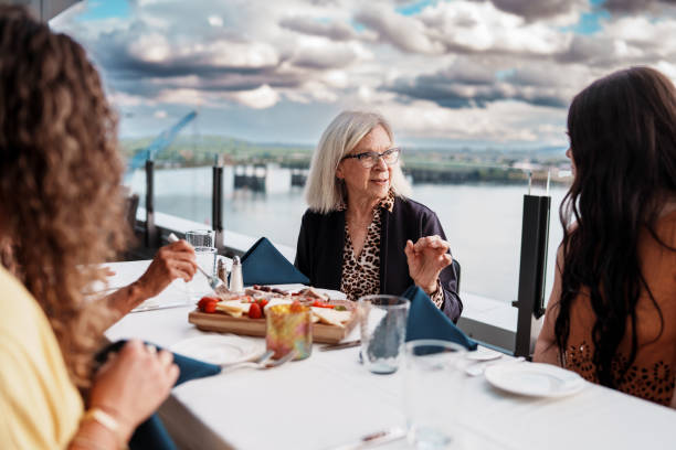istock Senior woman chatting with friends while enjoying dinner out 2181566901