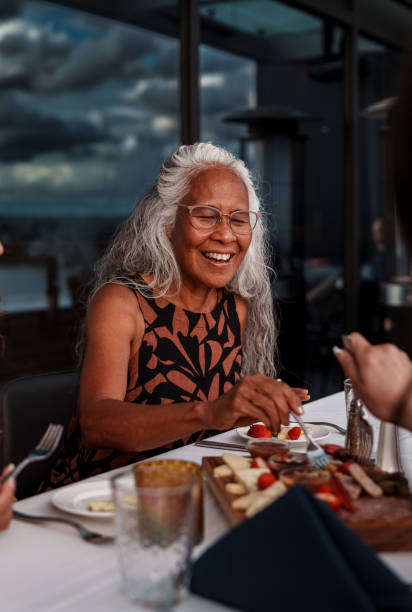 istock Beautiful senior woman sharing appetizer with friends while dining at restaurant 2181567023