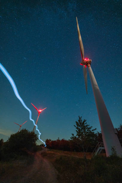 istock Wind turbines generating green energy under starry night sky 2181570358