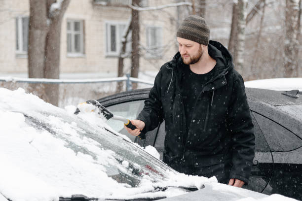 istock young man cleans car from snow 2181571970