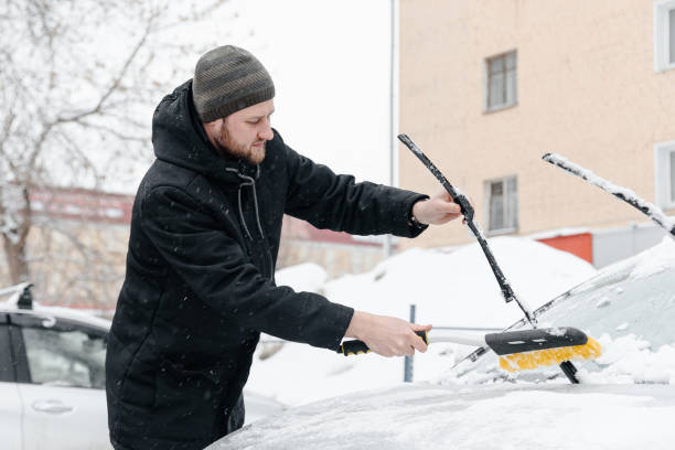 istock young man cleans car from snow 2181571973